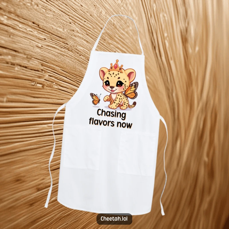 Funny cheetah cub wearing a tiara, playfully racing a butterfly, on a durable apron, perfect for kitchen fun, a great funny gift.